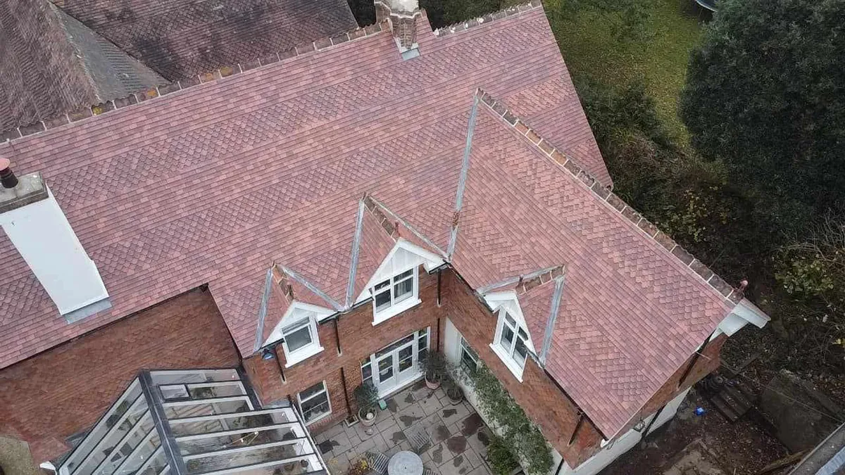 Drone view of a red brick house with a new clay plain tile roof and dormers