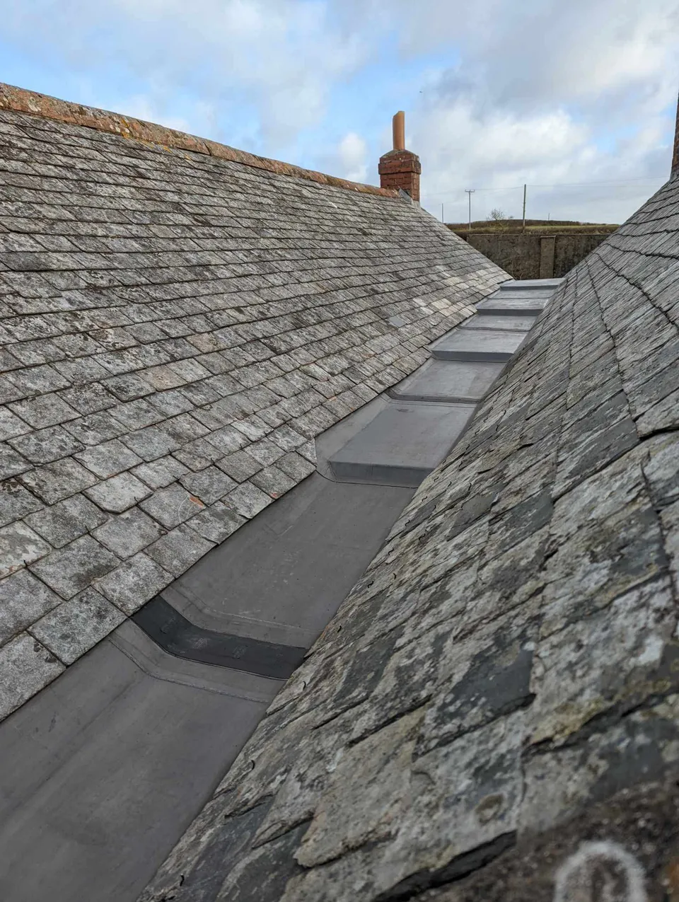 Lead-lined valley between two slate roofs, with stepped drips