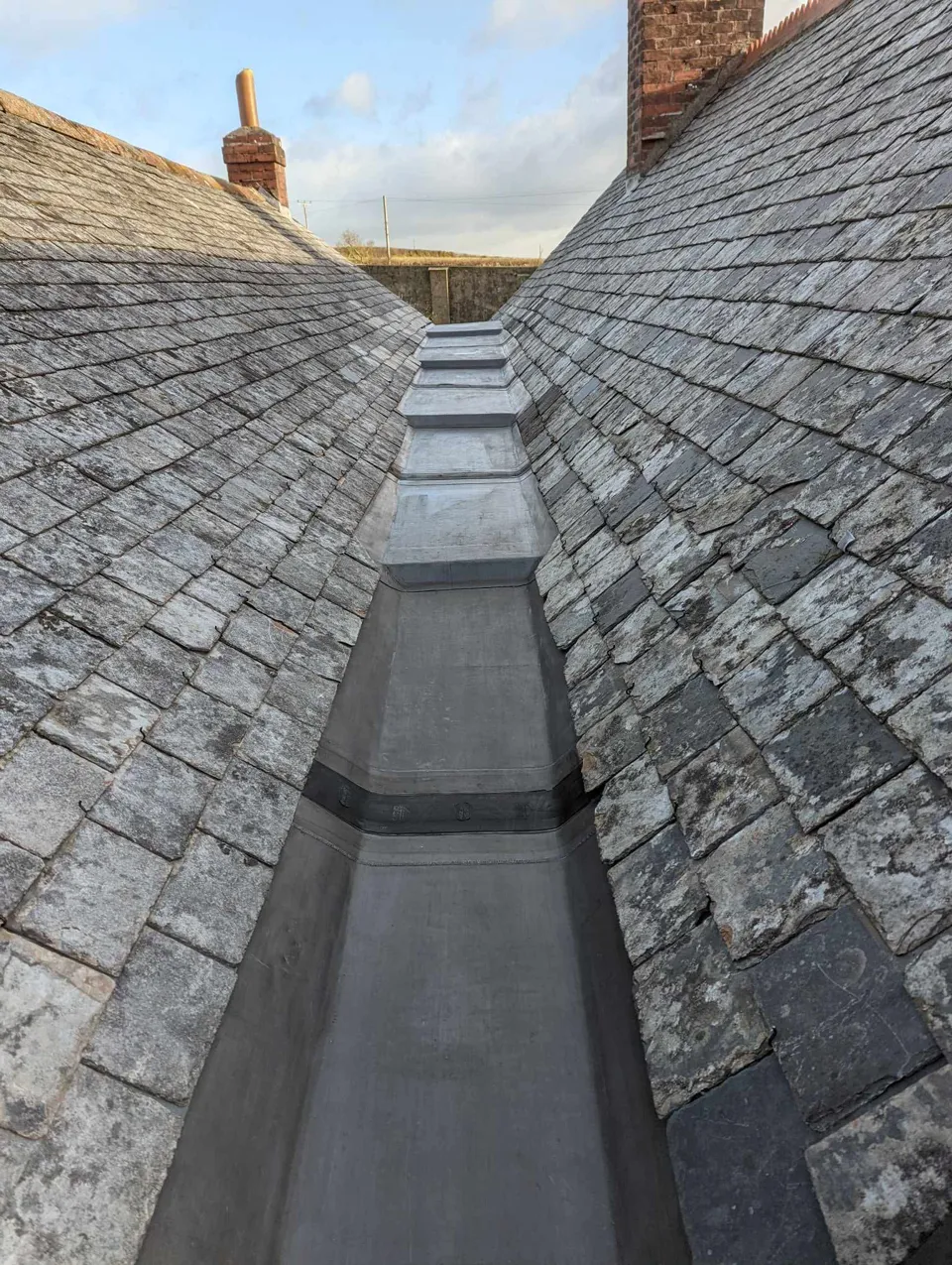 Lead gulley with stepped drips, between traditional slate roofs
